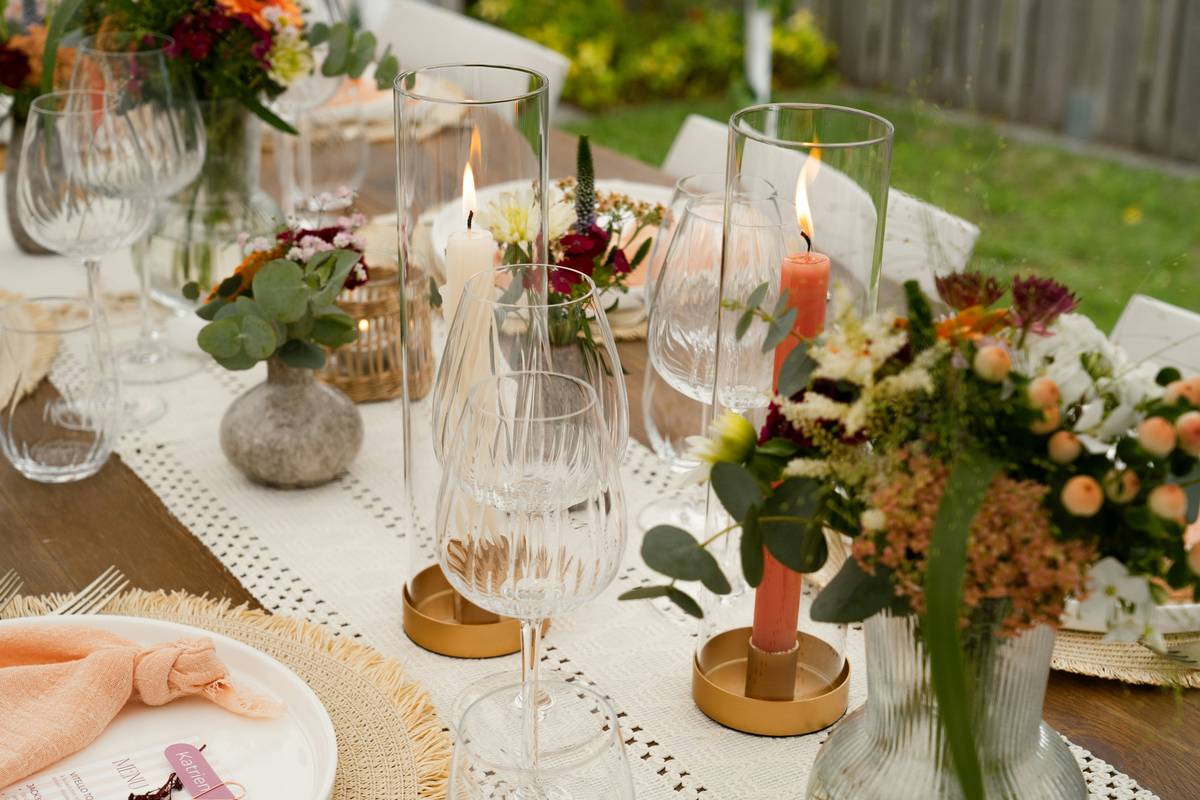 decorative candles and candle holders arranged on a wooden mantel with varying heights and textures