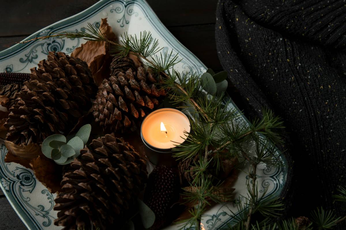 Minimalist candle holder decor featuring a single beeswax taper in handmade clay dish on a linen-covered side table