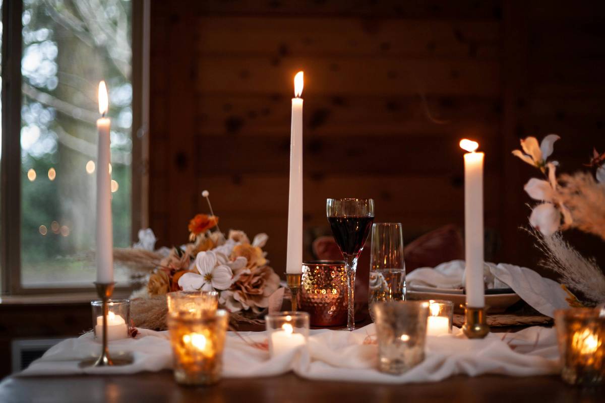 candle holder decor ideas featuring mixed-material holders on a wooden console table with greenery and books
