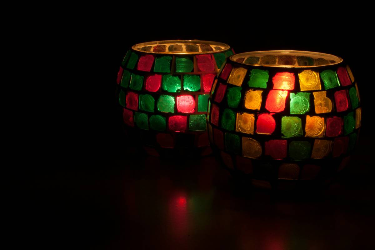 unique candle holders designs arranged on a rustic wooden mantle with white taper candles and dried eucalyptus